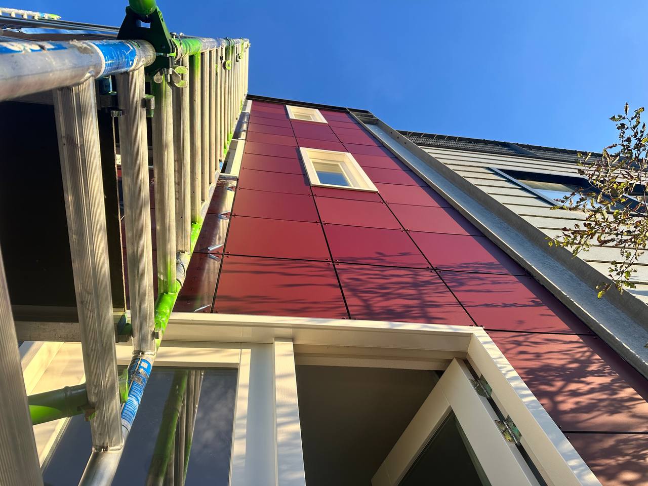 Gevelpanelen in bordeauxrood tijdens werkzaamheden rond raamopeningen