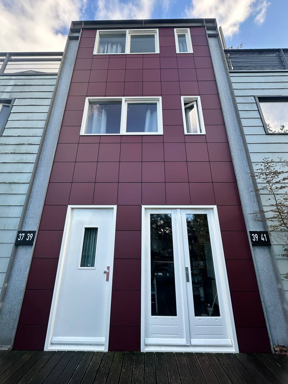 Totaalbeeld van een gevel met bordeauxrode panelen en witte kozijnen